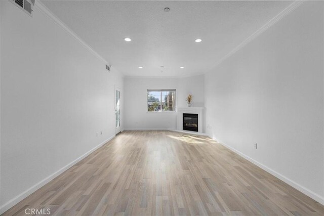 unfurnished living room featuring ornamental molding and light hardwood / wood-style floors