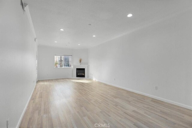 unfurnished living room featuring ornamental molding and light hardwood / wood-style floors