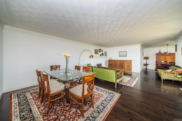 dining room featuring ornamental molding, dark hardwood / wood-style flooring, a brick fireplace, and a textured ceiling