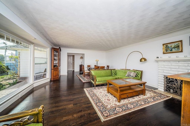 living room featuring dark hardwood / wood-style floors, a brick fireplace, and a textured ceiling