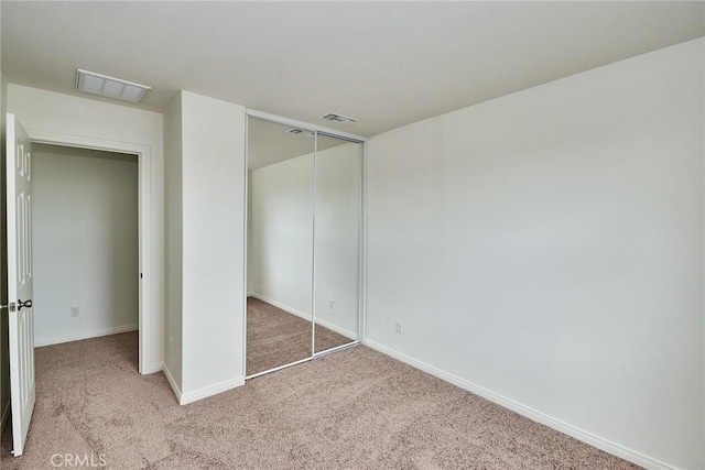 unfurnished bedroom with light colored carpet and a closet