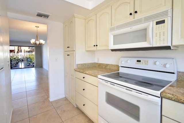 kitchen with light stone counters, a chandelier, hanging light fixtures, light tile patterned floors, and white appliances