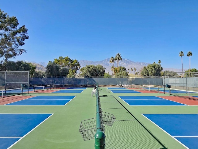 view of tennis court featuring basketball hoop and a mountain view