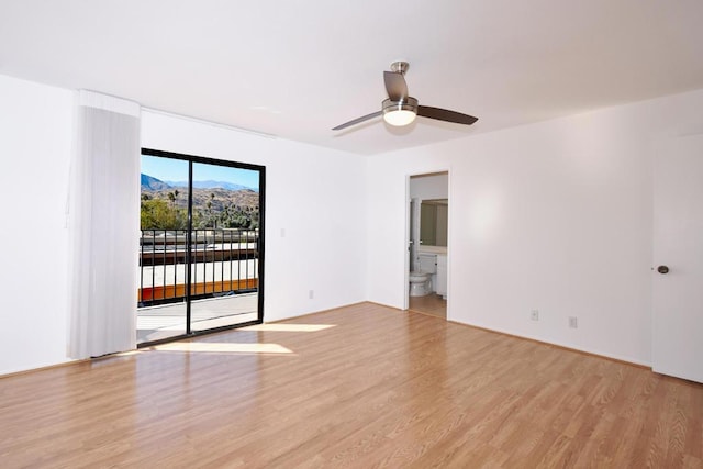 unfurnished room with ceiling fan, a mountain view, and light hardwood / wood-style floors