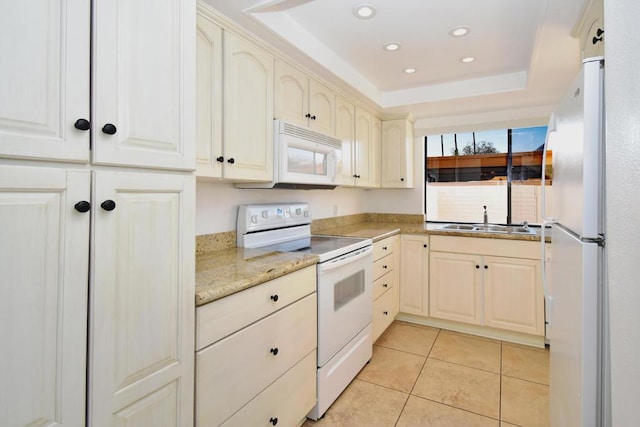 kitchen with sink, white appliances, light tile patterned floors, light stone counters, and a raised ceiling