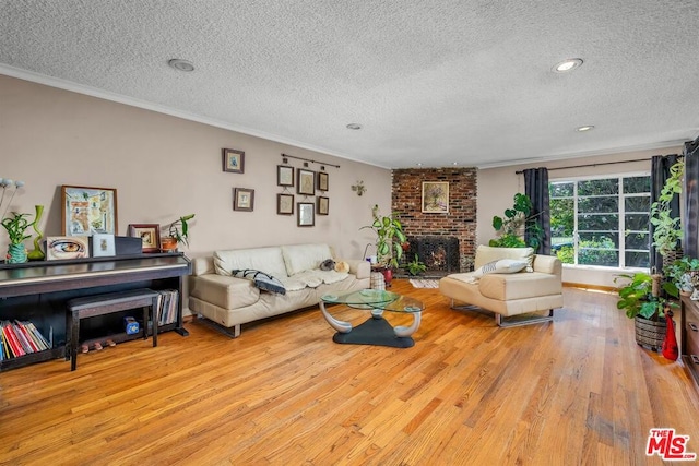 living room featuring crown molding, a fireplace, a textured ceiling, and light wood-type flooring