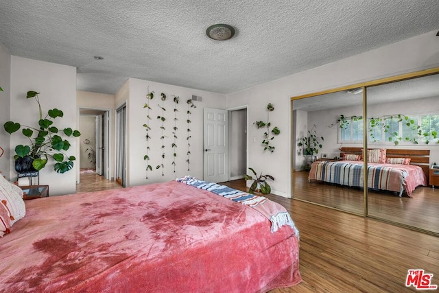 bedroom featuring wood-type flooring, a closet, and a textured ceiling