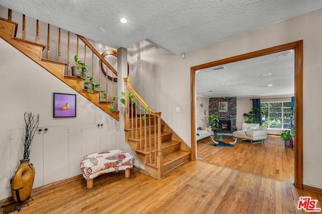 stairway featuring wood-type flooring, a fireplace, and a textured ceiling