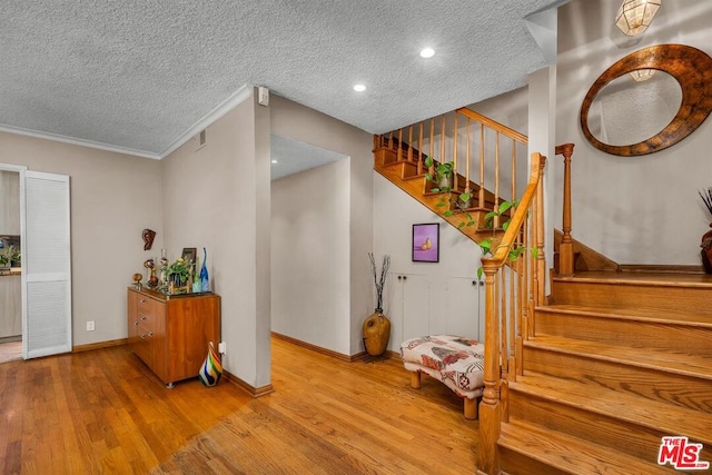 interior space featuring hardwood / wood-style flooring, crown molding, and a textured ceiling