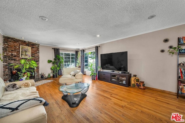 living room with hardwood / wood-style floors, a fireplace, ornamental molding, and a textured ceiling