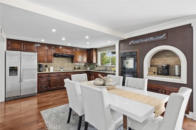 dining space with hardwood / wood-style floors, sink, and ornate columns