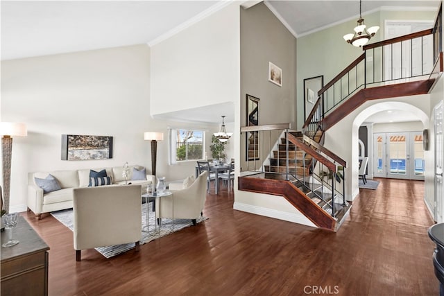 living room featuring a notable chandelier, hardwood / wood-style flooring, ornamental molding, and french doors