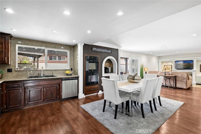 dining room with dark hardwood / wood-style flooring, sink, and ornate columns