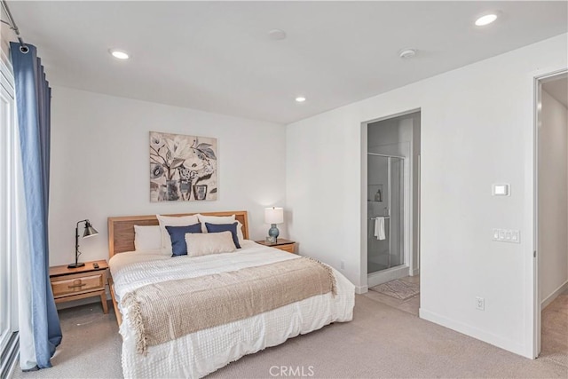 bedroom with ensuite bathroom and light carpet