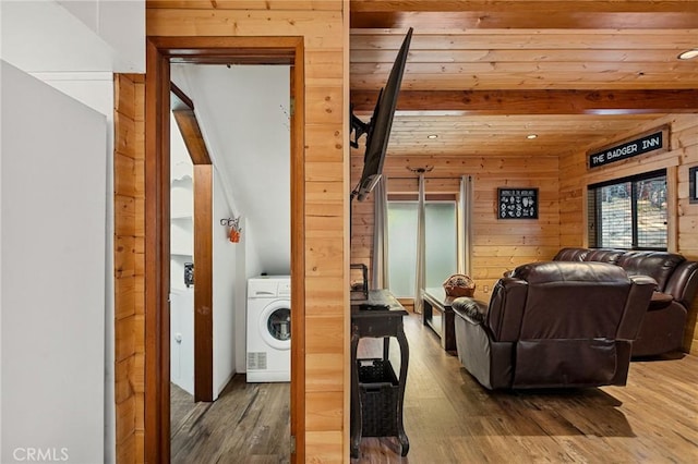 living area featuring wooden walls, wood finished floors, beam ceiling, and washer / dryer
