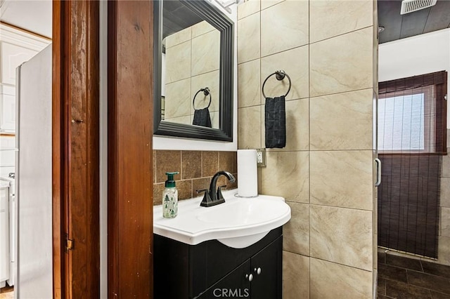 bathroom with tile walls, visible vents, vanity, and tasteful backsplash