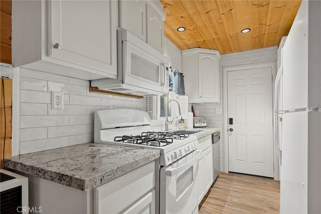 kitchen featuring white appliances, white cabinetry, a sink, backsplash, and wood ceiling