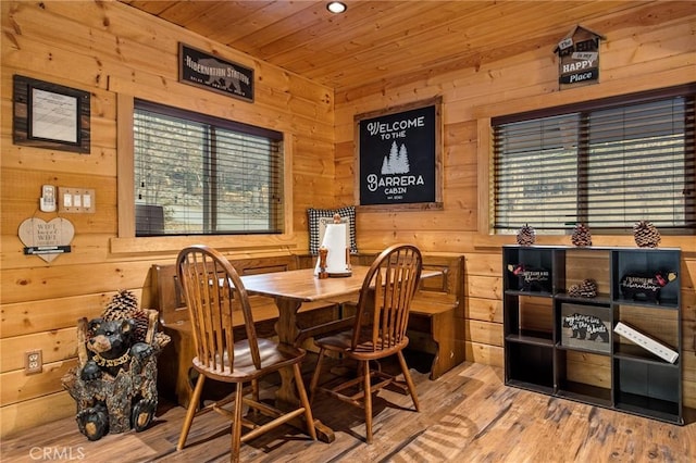 dining room with wood finished floors, wooden ceiling, and wood walls