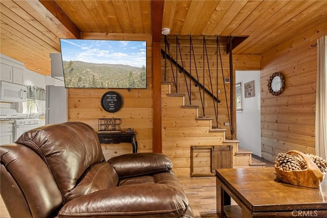 living area with light wood-style flooring, wooden walls, stairway, and wood ceiling
