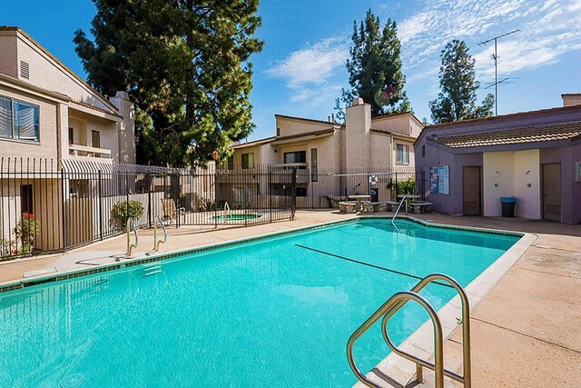 community pool featuring a residential view, a patio area, and fence