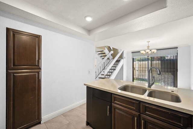 kitchen featuring light tile patterned floors, decorative light fixtures, a sink, light countertops, and a notable chandelier