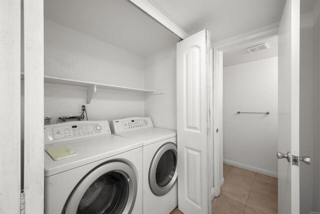 laundry area featuring washing machine and clothes dryer, light tile patterned floors, visible vents, laundry area, and baseboards