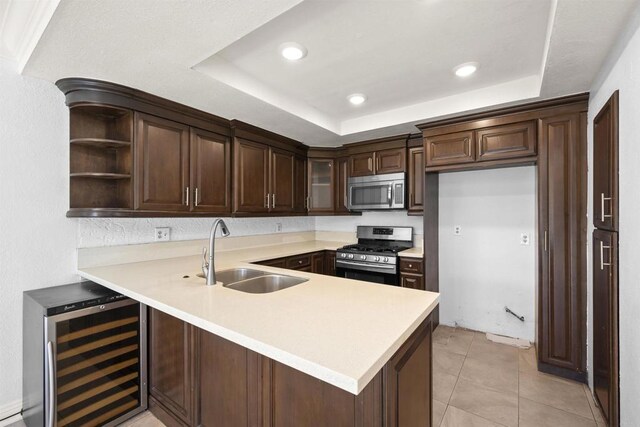 kitchen featuring wine cooler, stainless steel appliances, a peninsula, a sink, and a tray ceiling