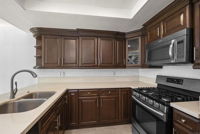 kitchen with stainless steel appliances, a sink, light countertops, open shelves, and glass insert cabinets