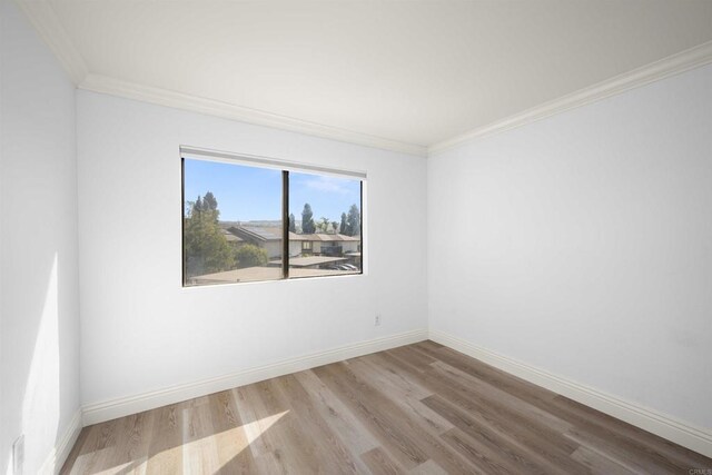 unfurnished room with light wood-style floors, crown molding, and baseboards