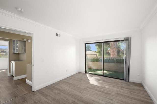 unfurnished room featuring crown molding, visible vents, plenty of natural light, and wood finished floors