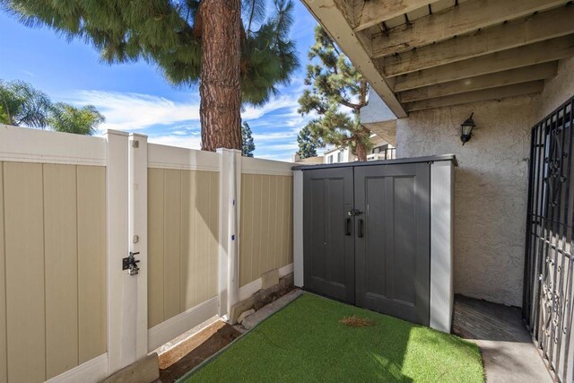 view of gate featuring a storage unit, fence, and an outdoor structure