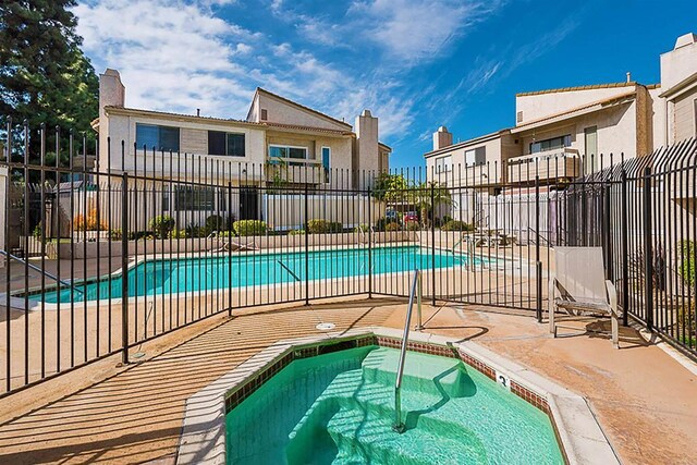 community pool featuring a hot tub, fence, and a patio