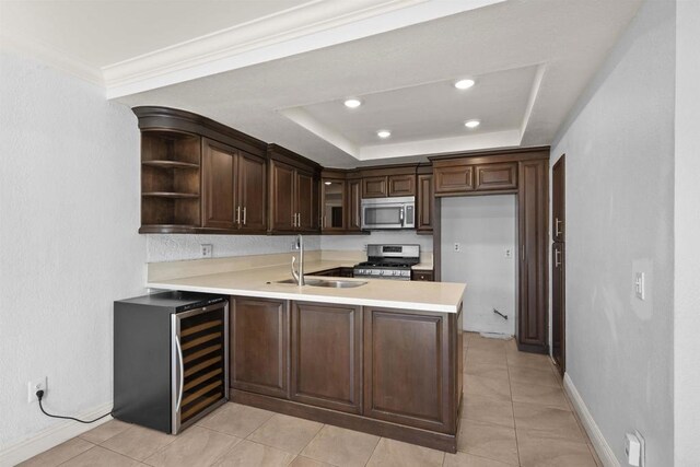 kitchen featuring stainless steel appliances, light countertops, a sink, and a peninsula