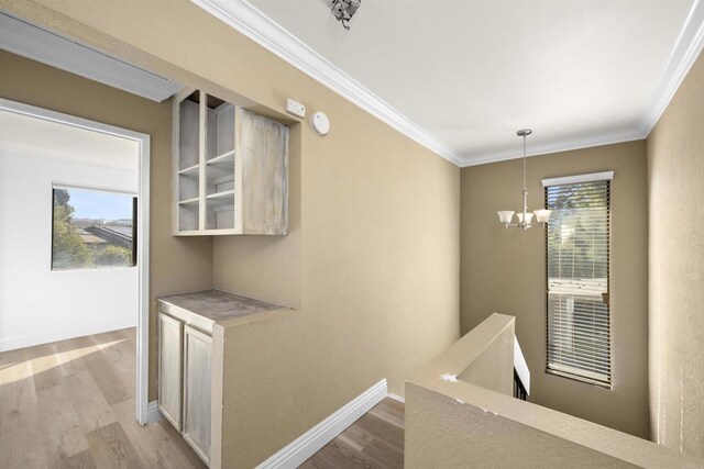 hall with baseboards, light wood-style floors, an upstairs landing, and crown molding