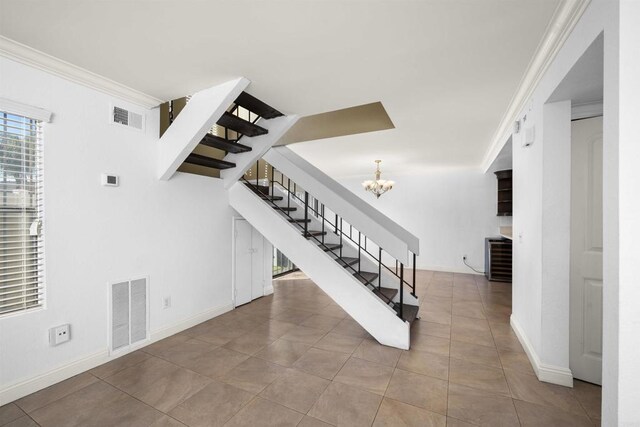 stairs with ornamental molding, visible vents, a notable chandelier, and tile patterned floors