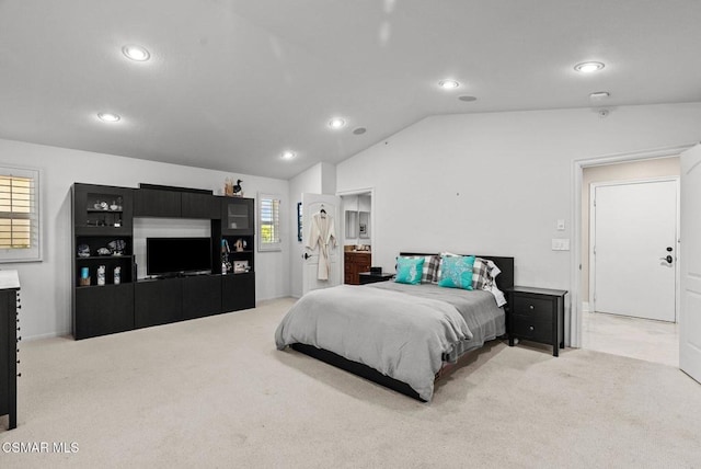 bedroom with light colored carpet, connected bathroom, vaulted ceiling, and multiple windows