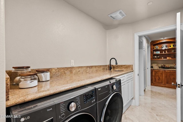 clothes washing area featuring cabinets, sink, and washer and dryer