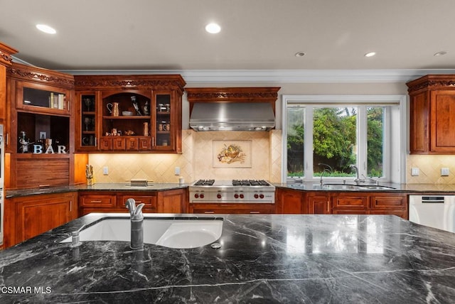 kitchen with sink, crown molding, dark stone counters, stainless steel appliances, and wall chimney range hood