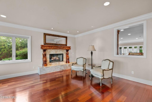 living area featuring a premium fireplace, crown molding, and hardwood / wood-style floors