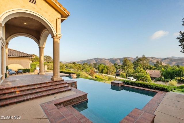 view of pool featuring a mountain view, a hot tub, and a patio