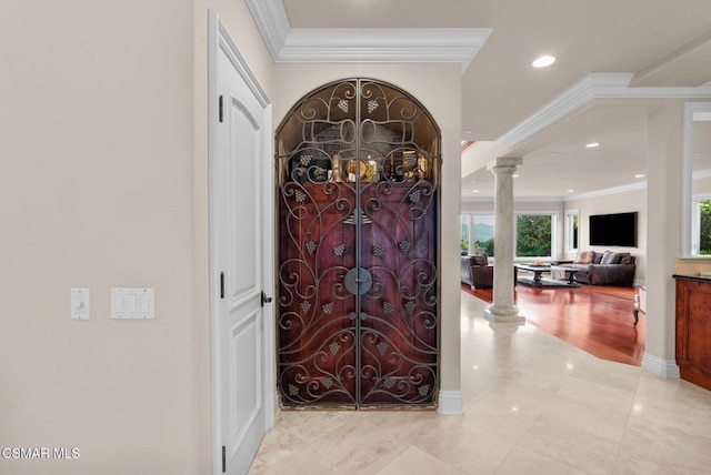 tiled foyer with crown molding and ornate columns