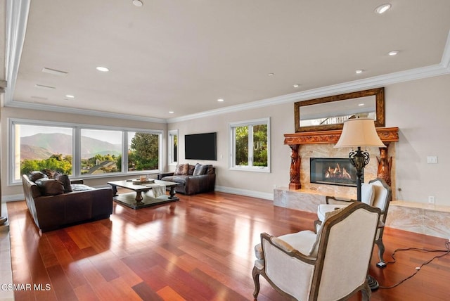 living room with hardwood / wood-style flooring, a high end fireplace, and ornamental molding