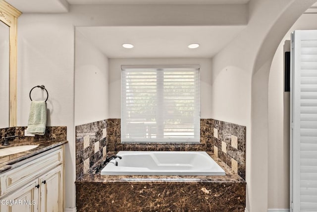 bathroom featuring vanity and tiled tub