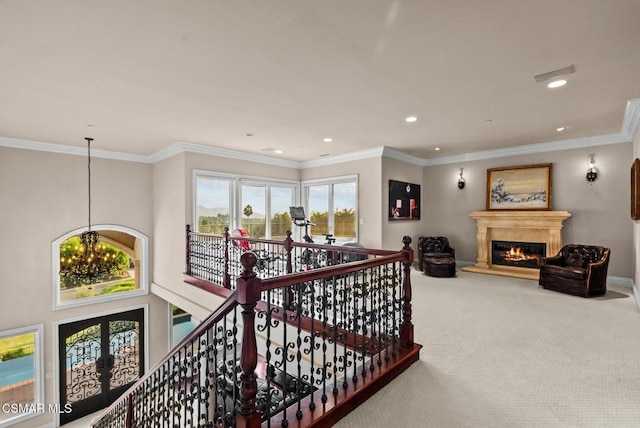 hallway featuring an inviting chandelier, ornamental molding, and carpet