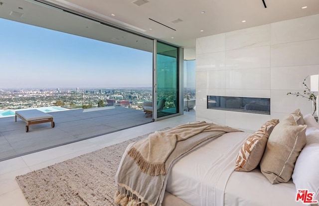 bedroom featuring light tile patterned floors, a tile fireplace, and expansive windows