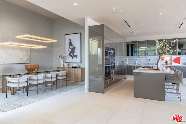 kitchen featuring double oven, light tile patterned floors, a breakfast bar, and a kitchen island