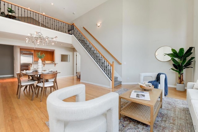 living room with a high ceiling, an inviting chandelier, and light hardwood / wood-style flooring