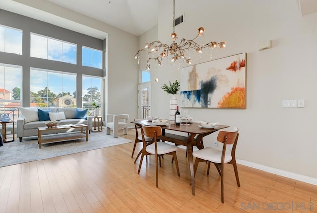 dining area with a high ceiling, a chandelier, and light hardwood / wood-style floors