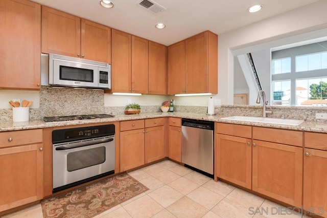 kitchen with stainless steel appliances, tasteful backsplash, light stone countertops, and sink