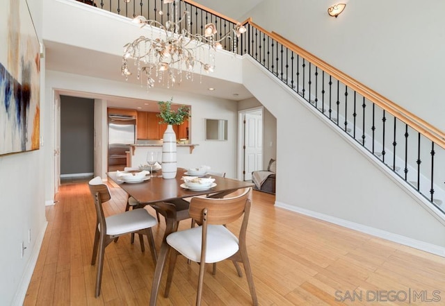 dining room featuring a chandelier, a high ceiling, and light wood-type flooring